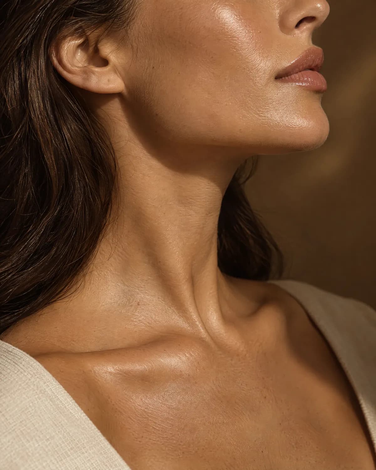 A woman's jawline and neck in profile with glowing, hydrated skin