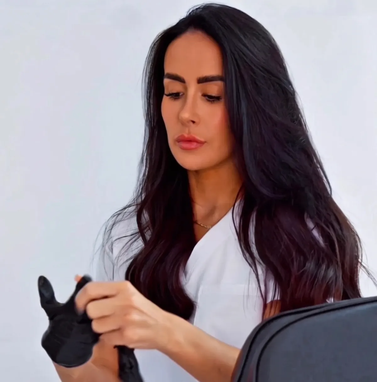 Rebecca in her white uniform, pulling on black treatment gloves